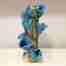 A long tall vase with blue labia flowers draped around it.
