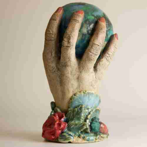 A stoneware ceramic sculpture of a woman's hand holds the whole world