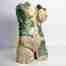 a feminine stoneware sculpture where glossy green monstera leaves entwine with a raw, cracked female torso.