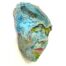 A wall hanging ceramic sculpture of a resting female face. She is covered with a multitude of green, turquoise and pink textured glazes.