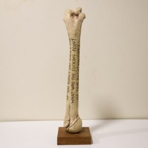 sculpture of a human bone with words carved into it.